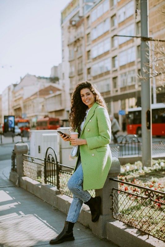 dosc-mloda-kobieta-za-pomoca-smartfona-na-ulicy-i-trzymajac-kawe-na-wynos