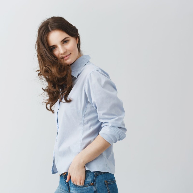 portrait-student-girl-with-dark-long-wavy-hair-holding-hands-pockets-with-calm-happy-face-expression